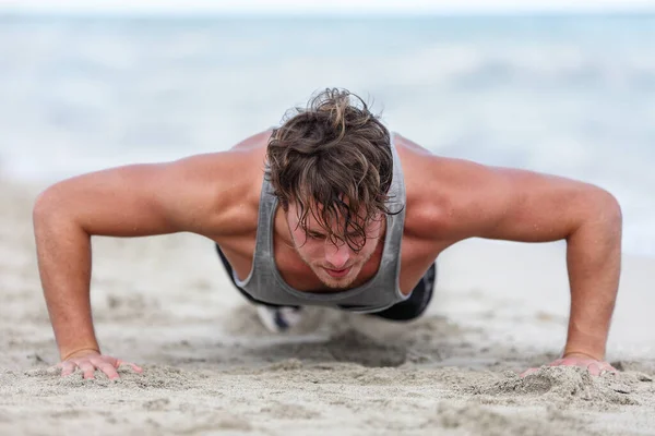 Fit Fitness człowiek ćwiczenia mięśni ramion robi ćwiczenia pompki ćwiczenia. Biały mężczyzna fitness atleta model cross-training push-up na plaży na świeżym powietrzu. Trener pompek ćwiczy latem na plaży. — Zdjęcie stockowe