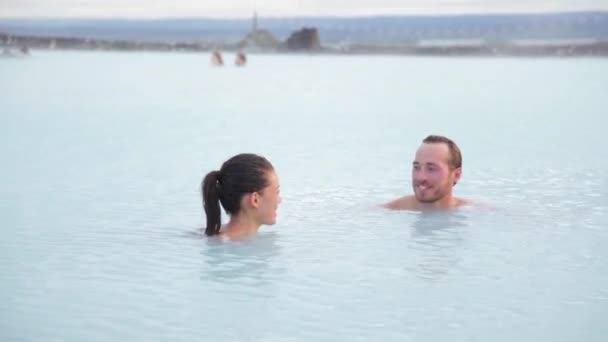 아이슬란드의 온천 지열 온천입니다. 사랑에 빠진 로맨틱 한 커플 이 아이슬란드의 온천에서 휴식을 취하는 모습. 젊은 남녀가 푸른 개펄에서 목욕을 즐기며 아이슬란드의 관광객들의 눈길을 끌고 있다. 석양 — 비디오