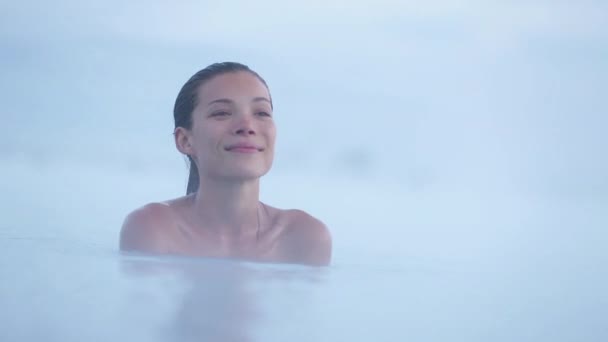 IJslandse geothermische spa. Een vrouw die ontspant in een warm lentezwembad op IJsland. Meisje geniet van zwemmen in een blauwe lagune IJslandse toeristische attractie — Stockvideo