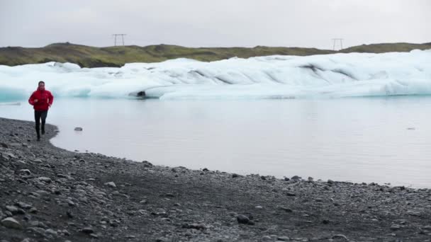 İzlanda 'daki Jokulsarlon Buzul Gölü' ndeki buzdağları tarafından güzel doğa manzarasında koşmak için koşan koşucu izleri. — Stok video