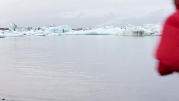 アイスランドのジョクルサロン氷河湖で氷山によって男を実行しています。リアルタイム — ストック動画