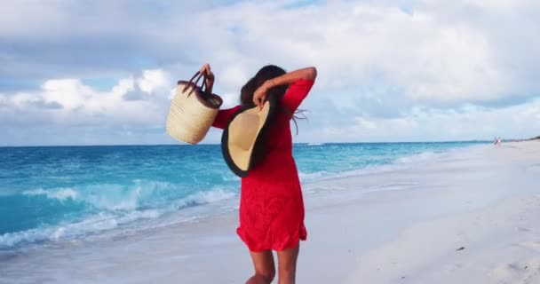 Vacaciones de lujo en la playa elegante dama corriendo divirtiéndose emocionada, eufórica, feliz, animando llena de alegría saltando y bailando en las vacaciones de playa con ropa de playa, sombrero de sol, bolsa de paja roja y vestido de encubrimiento — Vídeo de stock