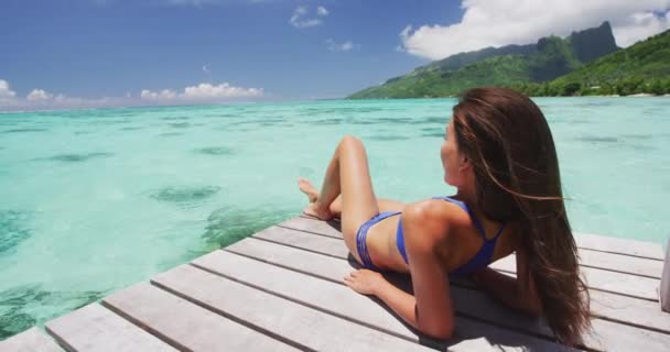 Sunbathing woman in bikini at Luxury travel holiday destination on overwater bungalow villa at Tahiti resort tropical holiday, Moorea, Tahiti, Polinésia Francesa — Vídeo de Stock