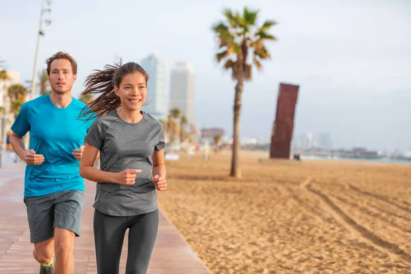 Sport sommar aktiv livsstil passar människor som tränar på stranden i Barcelona. Utomhus motion friska par löpare utövar. Vänner interracial idrottare glada träna utanför — Stockfoto