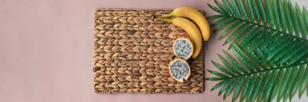 Pitaya ve muz tropikal meyveler kahvaltı masası arka planının en üst görüntüsü. Pembe pankart ve saman altlığı — Stok fotoğraf