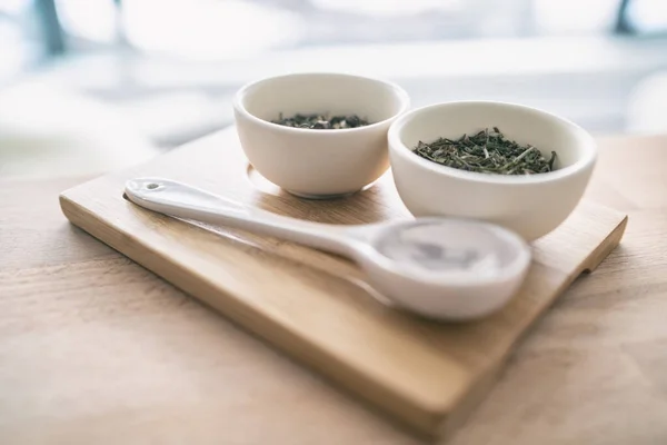 Sélection de thé vert de feuilles de Chine séchées en vrac pour la dégustation à la maison. Plateau en bois avec cuillère et tasses — Photo