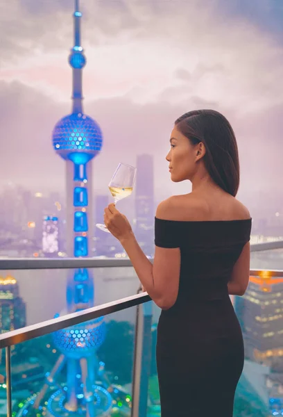 Stile di vita di lusso Shanghai donna asiatica bere vino bianco in Cina Viaggi. Elegante modello in abito nero sulla terrazza con vista sulla città, soggiorno di fascia alta. — Foto Stock