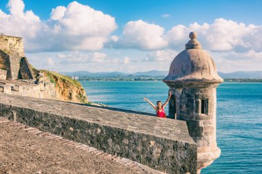 San Juan Puerto Rico travel happy Asian tourist woman excited with open arms in happiness at watch tower of Castillo San Felipe del Morro summer cruise vacation clipart