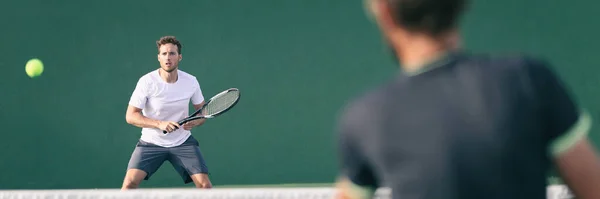 Tennis players playing on green court man focused on other player hitting ball with racket panoramic. Men sport athletes playing tennis match. Two professional tennis players outdoor during game — Stock Photo, Image