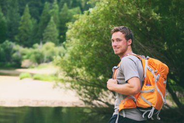 Summer camp young man on travel hike happy hiker walking with camping backpack in forest trek trail clipart