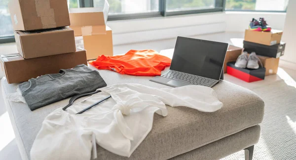 Online store selling new clothes from home. Small business working on laptop shopping for fashion clothing shipped in shipping cardboard boxes — Stock Photo, Image