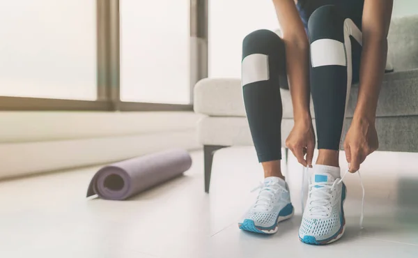 Mulher amarrando atacadores de tênis de corrida se preparando para voltar em forma indo para ioga ou pilates treinamento de classe de fitness em casa — Fotografia de Stock