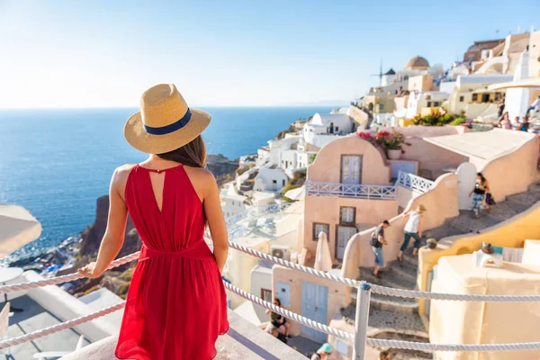 Vacaciones de viaje Grecia Santorini mujer de la isla en vestido rojo que viaja en Europa mirando a la vista del pueblo de Oia, vacaciones de lujo. Vacaciones de verano crucero destino — Foto de Stock