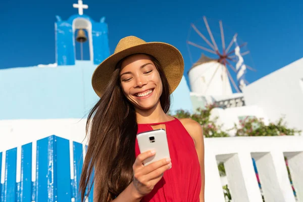 在著名的欧洲旅游胜地欧亚市蓝色教堂，年轻的亚洲女游客使用5克的手机发短信旅游数据应用程序进行旅游度假。暑假 — 图库照片