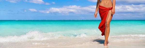 Depilacja laserowa depilacja nóg dla gładkiej skóry plaża gotowa wakacje kobieta spacerująca w tle oceanu panoramiczny baner. Spa wellness body w czerwonej spódnicy sarong — Zdjęcie stockowe