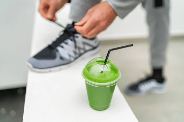 Sağlıklı yeşil smoothie yemek detoks yeme yaşam tarzı formda sporcu hazırlanıyor sabah yürüyüşü için ayakkabı bağlıyor kilo vermek için vegan diyeti içiyor antrenman yapıyor — Stok fotoğraf