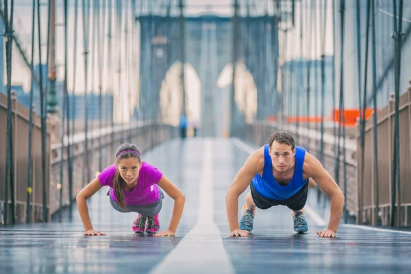 Fitness sportolók edzés szabadban csinál push-up gyakorlatok edzés Brooklyn Bridge, New York város, ázsiai nő és kaukázusi férfi, fajok közötti pár — Stock Fotó