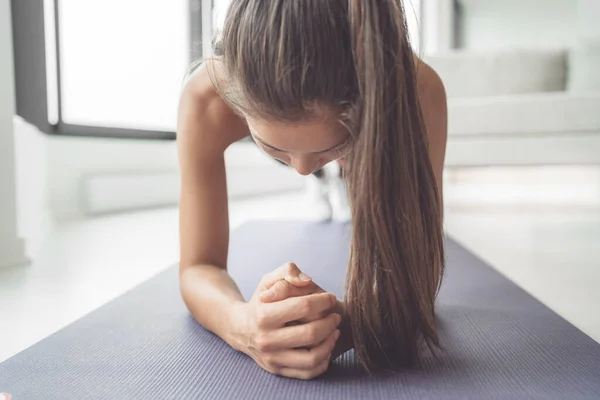 健身女孩在做举重运动的过程中滑板。女运动员在客厅里做瑜伽垫上的身体核心锻炼 — 图库照片