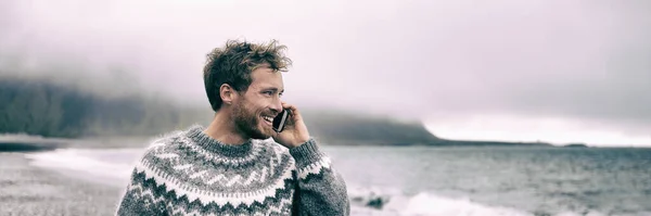 Giovane uomo che cammina sulla spiaggia parlando al telefono cellulare avendo conversazione con qualcuno durante la natura passeggiata invernale banner panoramico stile di vita all'aperto — Foto Stock