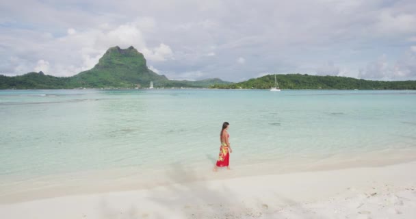 Utazás Francia Polinézia nyaralás. Egy nő sétál a Paradicsom motu strandon a Bora Borán az Otemanu hegyen. Boldog lány visel hagyományos pareo és Bikini Tahitin, Francia Polinézia — Stock videók
