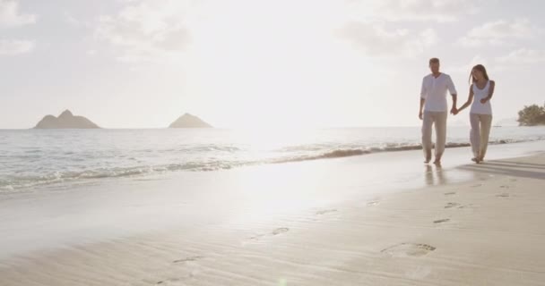 Paar bei Sonnenuntergang am Strand spaziert romantisch auf Flitterwochen auf Hawaii — Stockvideo