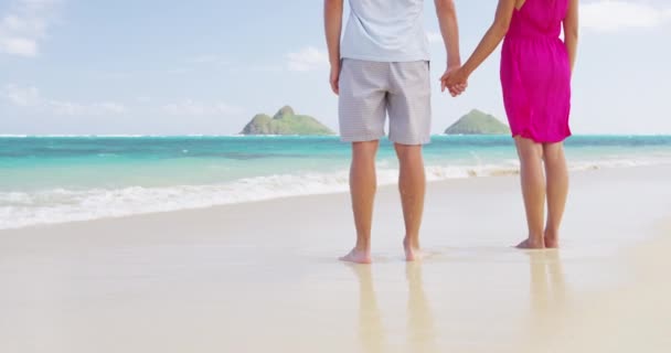 Отдыхающие путешествуют на пляже влюбленной парой, держась за руки в медовый месяц — стоковое видео