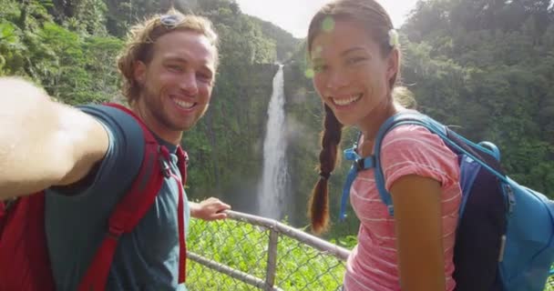 Χαβάη ζευγάρι τουρίστες λήψη ταξιδιωτικό τηλέφωνο selfie αυτο πορτρέτο με κάμερα τηλέφωνο στη Χαβάη, Big Islands, Akaka Falls. Ευτυχισμένο χαρούμενο νεαρό πολυπολιτισμικό ζευγάρι σε ταξίδια — Αρχείο Βίντεο