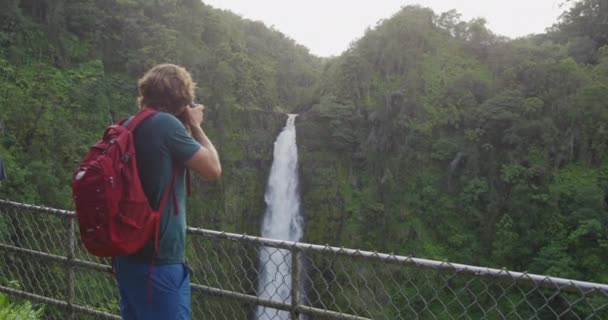 Hawaii turista fényképez esőerdőt, miközben túrázik a híres Akaka Falls State Park Hawaii, Big Island, USA. Az ember utazó DSLR kamerát használ utazáskor. Lassú mozgás. — Stock videók