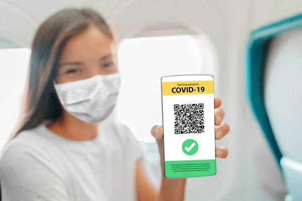 Вакцина паспорт на мобильном телефоне приложение экран женщина в маске во время полета показывая вакцинацию доказательства по прибытии в аэропорт для поездки в отпуск полет во время пандемии коронавируса — стоковое фото