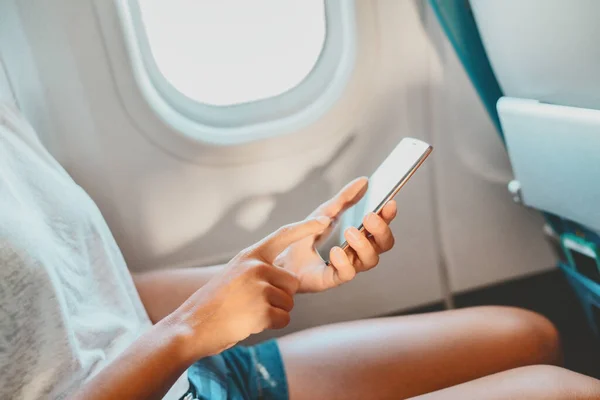 Mobiele telefoon met vrouw op de vlucht. Vliegtuigpassagier met behulp van mobiele telefoon app scherm voor vaccin paspoort bewijs bij aankomst naar de luchthaven voor vakantie reizen vliegen tijdens coronavirus pandemie — Stockfoto