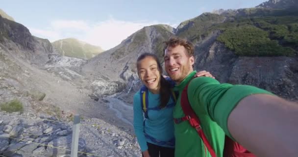 Paar selfie video - Nieuw-Zeelandse toeristen glimlachen gelukkig door Franz Josef Glacier — Stockvideo