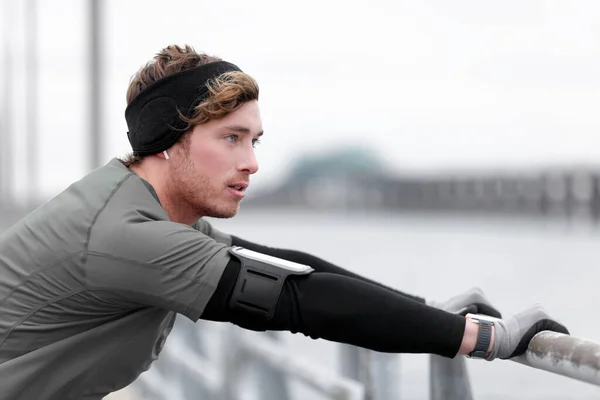 Winterhardloper training buiten met behulp van telefoon houder luisteren naar muziek met hoofdband koud weer accessoires dragen draagbare tech smartwatch — Stockfoto