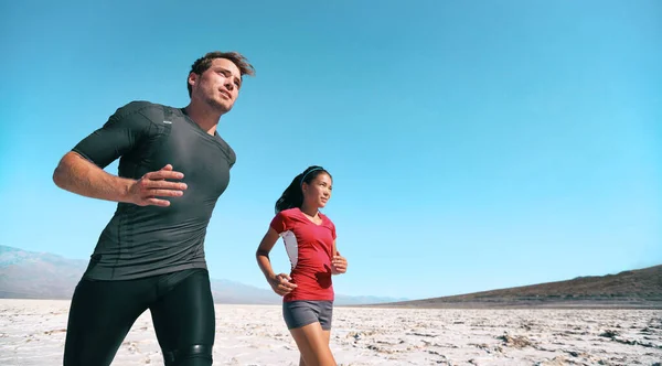 Sportovci vytrvalostní trénink v extrémním vedru venku běží v létě pouštní prapor. Žena a muž běžci venku. — Stock fotografie