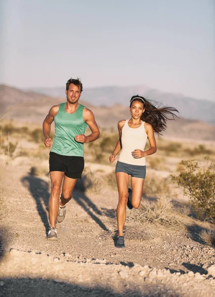 Runners koppel hardlopen lange afstand ultra trail run race. Runner man en sport vrouw trainen cardio buiten in cross country zonsondergang landschap. Fit mannelijke Kaukasische fitness model, Aziatische vrouwelijke atleet. — Stockfoto