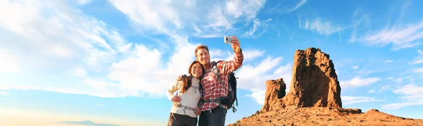 Selfie turistas tomando fotos con teléfono móvil en la cima de la montaña senderismo panorámica. Naturaleza trek pareja excursionistas senderismo con mochilas en Europa bandera panorámica. — Foto de Stock