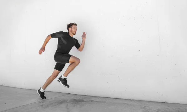 Sport atleet training loopt snel met explosieve sprint voor de concurrentie. Man loper uit te werken op fitness fitnessruimte outdoor witte muur achtergrond. — Stockfoto