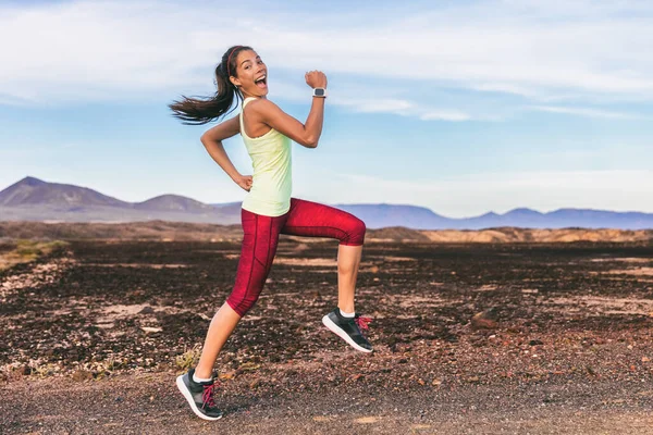 Leuke fitness workout personal trainer atleet vrouw gelukkig goofy springen om te motiveren hardlopen. Hoge knieën oefening benen training om vet training buiten te verbranden op pad lopen in de bergen natuur. — Stockfoto