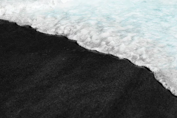 Beach bakgrundsvågor på vulkanisk svart sand konsistens tvättas över av vatten ocean våg flod. Caribbean Hawaii resor semester . — Stockfoto