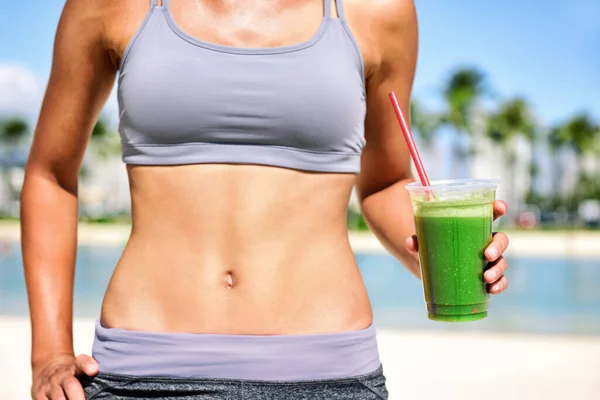 Green juice smoothie gezonde detox dieet gewichtsverlies fit vrouw drinken sap op outdoor strand zomer levensstijl. Buik en plastic beker. — Stockfoto