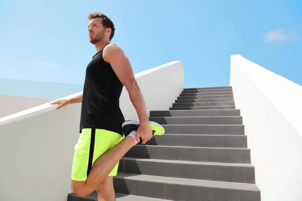 Bacak kasları esnek adam koşucusu ısınma egzersizleri için bacaklarını esnetmeye hazırlanıyor kardiyo HIIT yaz antrenmanı için açık hava merdivenlerinde egzersiz yapıyor.. — Stok fotoğraf