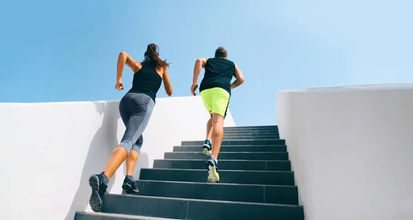 Escaleras corredores corriendo por escaleras entrenamiento hiit entrenamiento. Pareja ejercitando piernas y cardio en gimnasio de fitness. Vida activa saludable deporte personas haciendo ejercicio escalada escalera en la ciudad urbana. —  Fotos de Stock