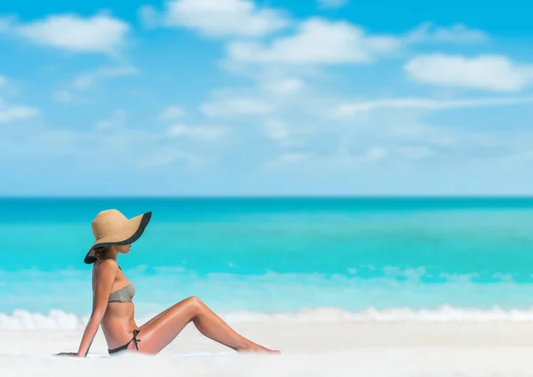 Praia mulher sol bronzeamento banhos de sol deitado na toalha de praia na areia corpo pele proteção exposição solar com chapéu para câncer de pele. — Fotografia de Stock