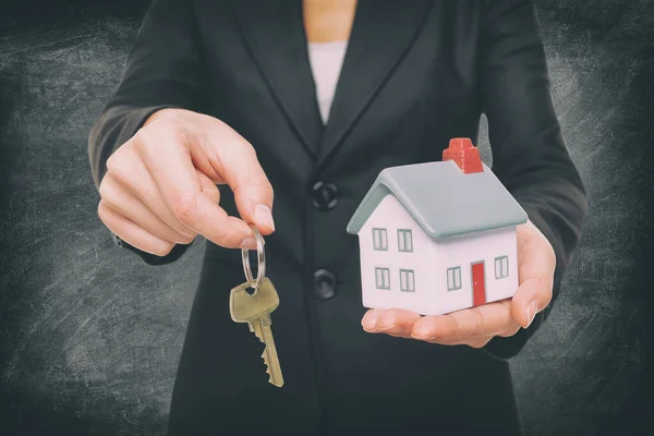 Zakup nowego pośrednika nieruchomości nieruchomości domu dając klucz domu pokazując miniaturowy pomysł zabawki domu — Zdjęcie stockowe