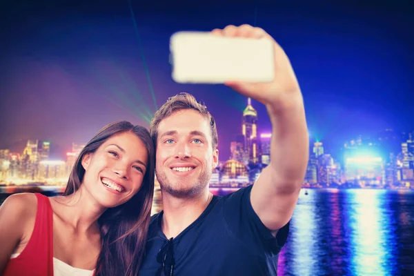 Пара путешественников сделала селфи с телефоном на фоне ночного светлого города на острове Гонконг в Китае. Стиль жизни молодежи — стоковое фото