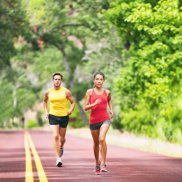 Läufer laufen auf der Straße vor zwei Athleten, die im Sommer im Freien joggen. Quadratische Ernte. Frau und Mann liefern sich Rennen — Stockfoto