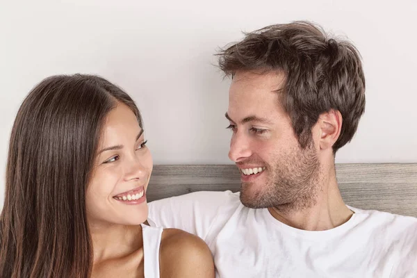 Gelukkig paar in liefde glimlachen naar elkaar kijken in hun ogen portret thuis van interraciale relatie aziatische vrouw, blanke man — Stockfoto