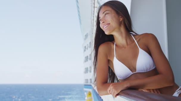 Young woman in swimsuit standing on cruise ship at sunny day looking at sea — Video