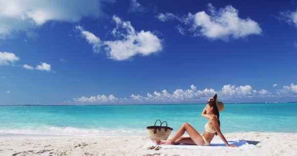 Strandfrau Sonnenbräune im tropischen Sommerurlaub bei perfektem Himmel mit blauem Himmel. Mädchen im niedlichen Retro-Streifen-Bikini und Hut-Outfit mit Strohtasche und Handtuch — Stockvideo