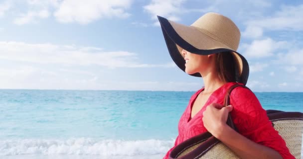 Mulher turista andando em férias tropicais de verão usando chapéu de sol, vestido vermelho e saco de praia relaxante em férias de viagem. Jovem senhora por trás em moda de luxo beachwear — Vídeo de Stock
