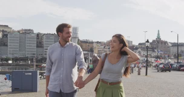 情侣手牵手在斯德哥尔摩，瑞典，欧洲。快乐的多种族年轻夫妇走在外面。斯堪的纳维亚男子、亚洲妇女 — 图库视频影像